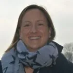 Eleanor Clarke, a woman in a scarf, smiles warmly; she is an ILS Case Manager based in Cheltenham, Gloucestershire.