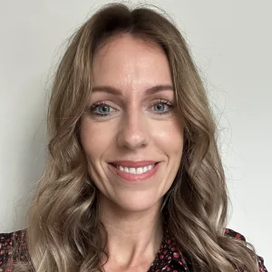 Based in Manchester, Cheshire, ILS Case Manager Jane Taylor is a woman with long hair, and is wearing a black and red shirt.