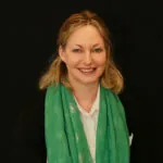 Based in Bournemouth, Dorset, ILS Case Manager Odile Waddington-Jones, poses in a white shirt with a green scarf draped around her neck.