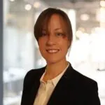 Sarah Rolfe, an ILS case manager from Sheffield, Yorkshire, stands in a business suit within a modern office environment.