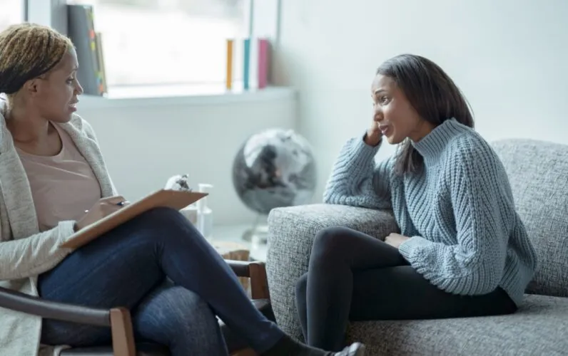 Two women on a couch, in conversation, representing the importance of hearing our clients voice in the article by Case Manager Imelda Molloy.