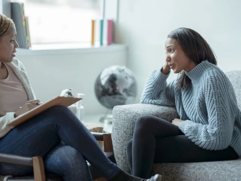 Two women on a couch, in conversation, representing the importance of hearing our clients voice in the article by Case Manager Imelda Molloy.